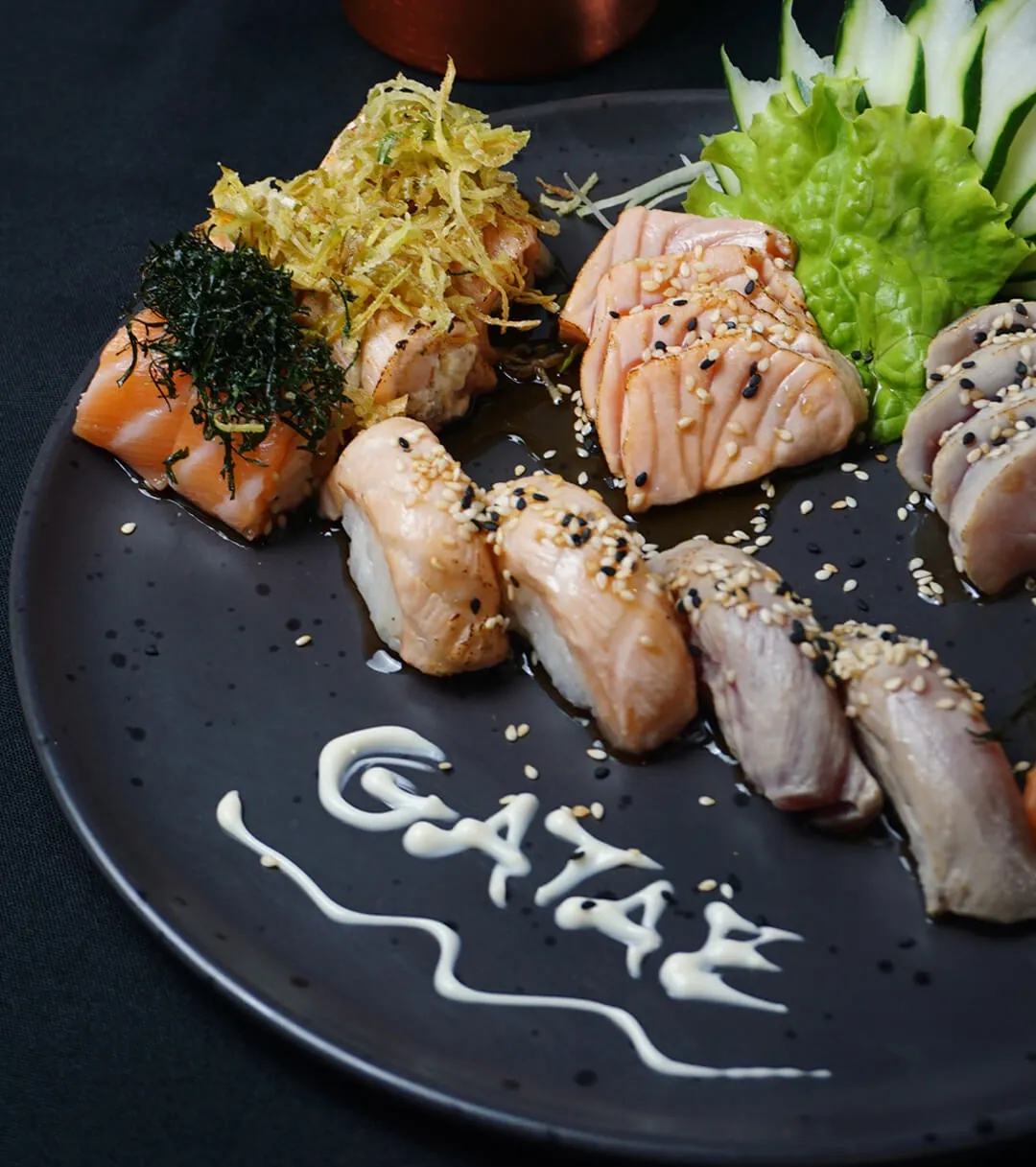 Sushis selados sobre prato preto com o nome Gatae desenhado em molho